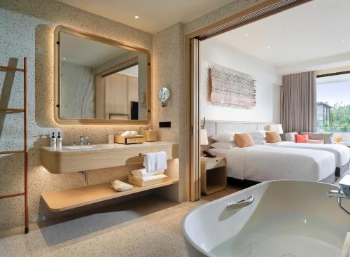 a bathroom with a tub and a bedroom with a bed at Chatrium Phuket Rawai in Rawai Beach