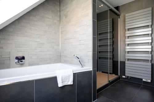 a bathroom with a bath tub and a shower at Le Vogelgarten in Zellenberg