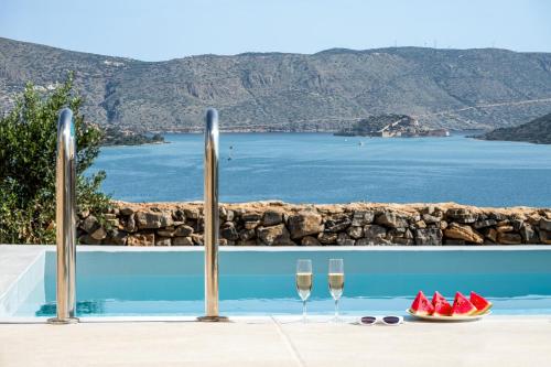 two glasses of wine next to a pool with watermelon at Elounda Heights (Adults Only) in Elounda