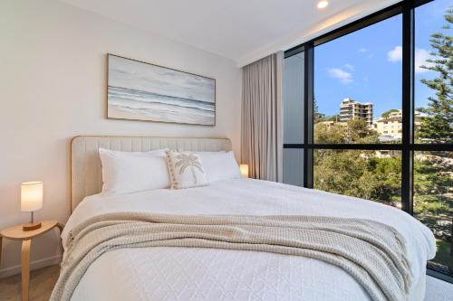 a bedroom with a bed and a large window at Luxury Esprit Apartment at Rainbow Bay in Gold Coast