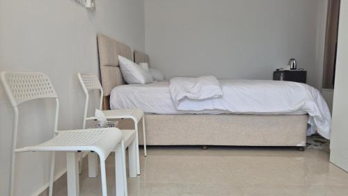 ein Schlafzimmer mit einem Bett und zwei weißen Stühlen in der Unterkunft غرفة الريف in Salalah