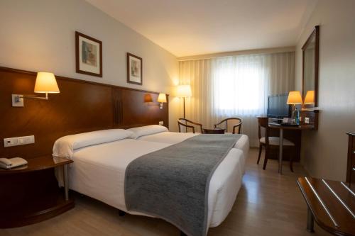 ein Hotelzimmer mit einem großen Bett und einem Schreibtisch in der Unterkunft Hotel Nexta Escaldes in Andorra la Vella