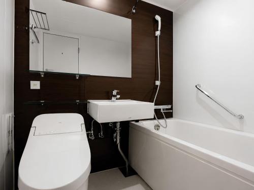 a bathroom with a toilet and a sink and a tub at Hotel JAL City Nagasaki in Nagasaki