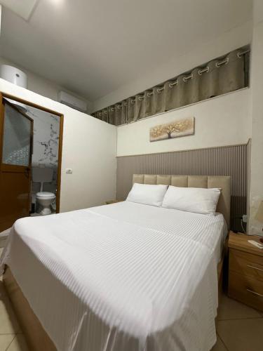 a bedroom with a large white bed and a bathroom at ORA Appartment's in Shkodër