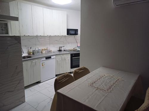 a kitchen with white cabinets and a table with chairs at Apartman Miljan in Trebinje