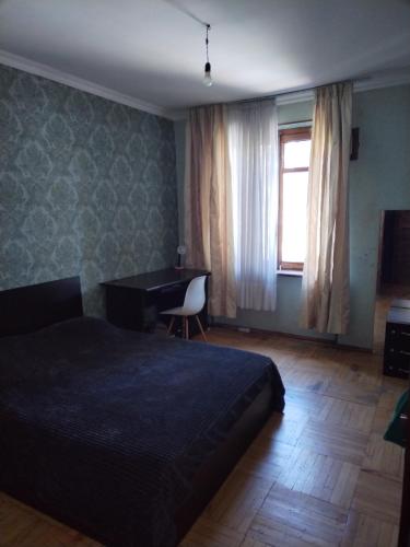 a bedroom with a bed and a desk and a window at Lalo in Tbilisi City