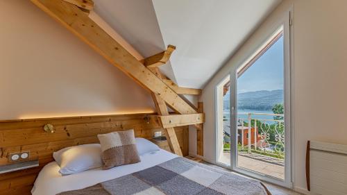 a bedroom with a bed and a large window at Villa Panoramique - Lac du Bourget in Bourdeau