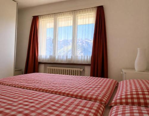 a bedroom with a bed and a window with red curtains at Revier Lärchenglück in Braunwald