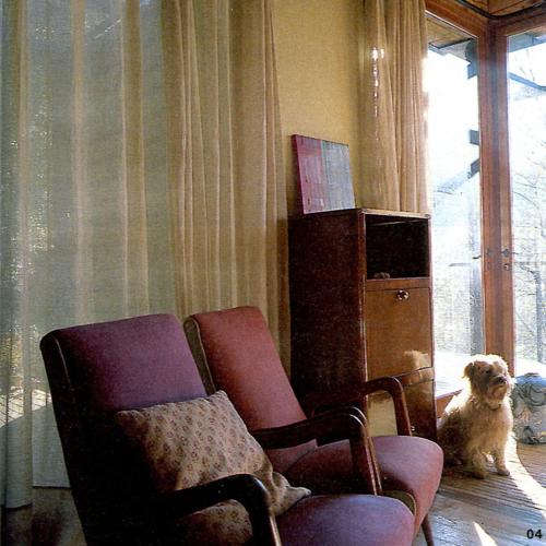 a dog sitting in a living room next to a chair at La Farga de la Muga in Sant Llorenç de la Muga