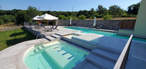 a swimming pool with a table and an umbrella at Agriturismo Gradec in Aurisina