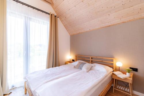 a bedroom with a large bed and a large window at Nadmorska Otulina - Nowoczesne dwupoziomowe domki nad morzem z dużym ogrodem in Ustka