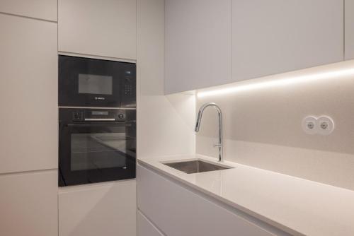 a white kitchen with a sink and a microwave at Aposentus - Sal D 'Ouro Exclusive in Canidelo