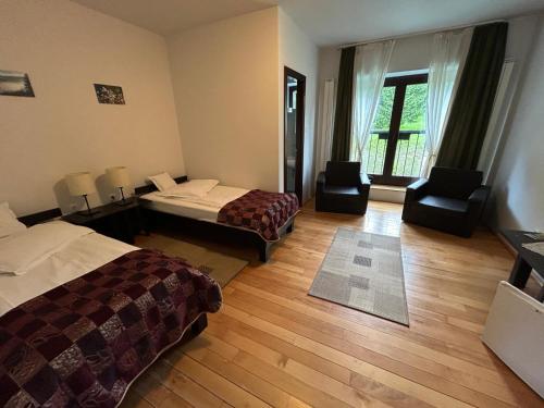 a hotel room with two beds and two chairs at Mountain-Rest Pension in Miercurea-Ciuc