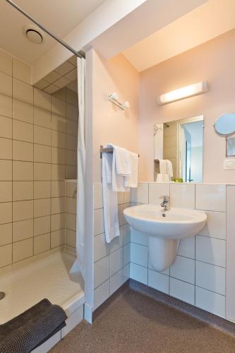 a bathroom with a sink and a shower at Logis Hôtel Restaurant de la Dore in Vertolaye