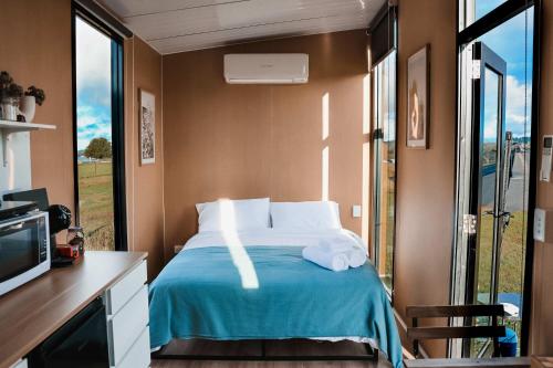 a bedroom with a bed with a blue blanket at Pasture and Paws by Tiny Away in Leeville