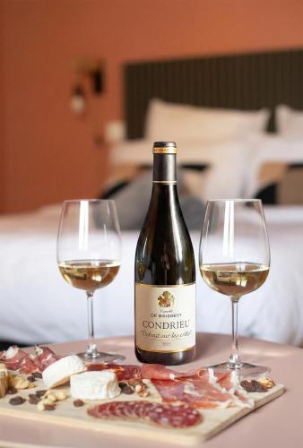 a bottle of wine and two glasses on a table at Vina Rhona - Loft de charme entre Rhône et Vignes climatisé in Condrieu