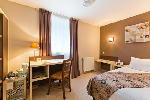 a hotel room with a bed and a desk and a bed at Logis Hôtel Restaurant de la Dore in Vertolaye