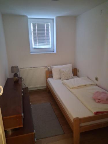 a small bedroom with two beds and a window at Apartman Vojinovic in Arandelovac