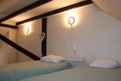 a bedroom with two beds and two lights on the wall at Le génépi in Roubion