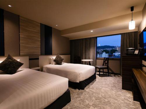 a hotel room with two beds and a television at Hotel JAL City Nagasaki in Nagasaki