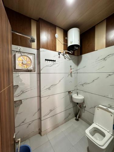 a bathroom with a toilet and a clock on the wall at The Empire Hotel in Sewāni
