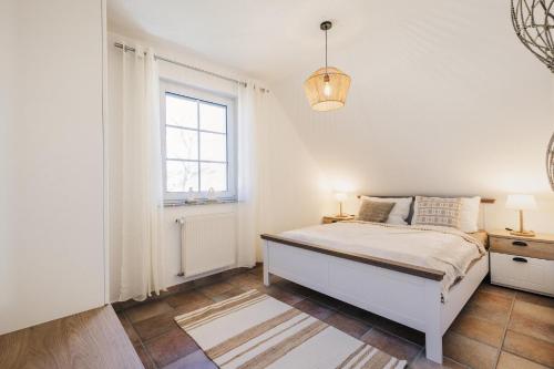 a white bedroom with a bed and a window at Rauchschwalbe in Zingst