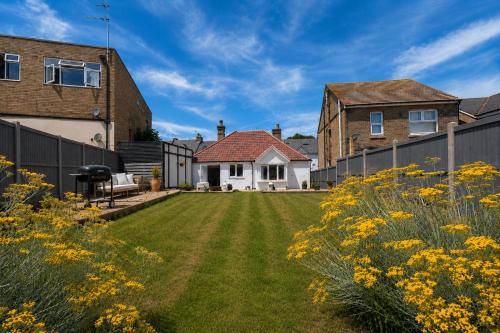 a garden with yellow flowers in front of a house at Beach Cottage Pets Welcome Sleeps 6 in Broadstairs