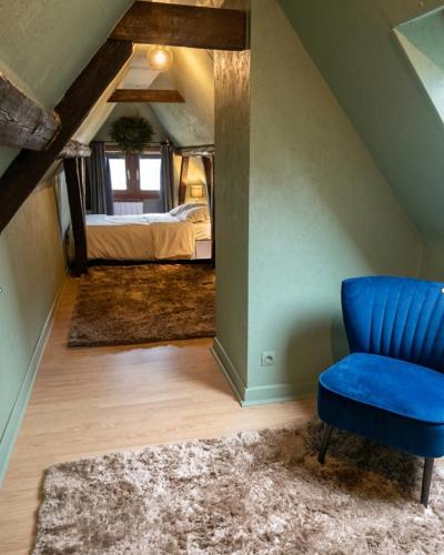 a bedroom with a blue chair and a bed at Escapade en Alsace - gîte de charme pour deux à Bergheim in Bergheim