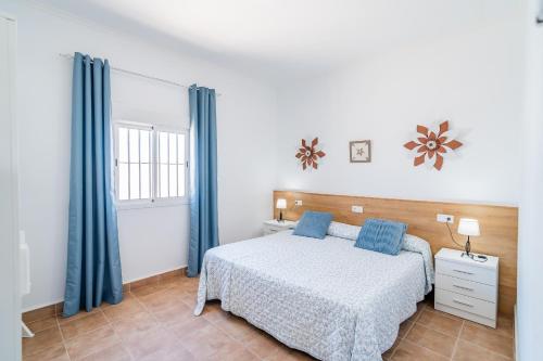 a bedroom with a bed with blue curtains and a window at Casa Rural Rafael in La Lantejuela