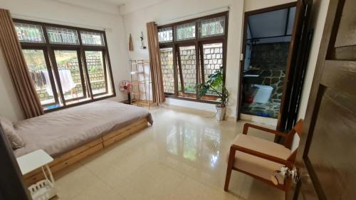 a bedroom with a bed and two windows and a chair at SugarHouse in Da Thanh