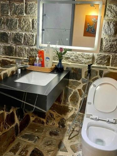 a stone bathroom with a sink and a toilet at SugarHouse in Da Thanh
