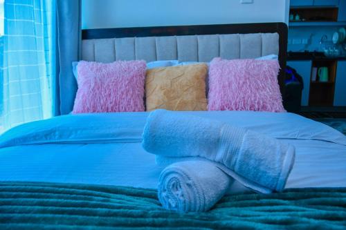 a blue bed with pink and blue pillows on it at Kiesth Whiskaway in Kiambu