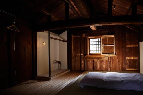 a bedroom with a bed and a window at 蔵宿あさぎやみたけ in Ome