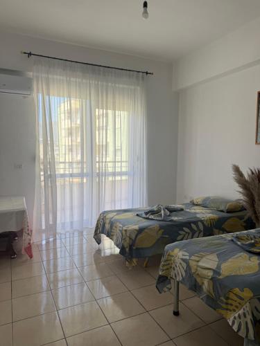 a bedroom with two beds and a large window at AS Orikum 1 in Orikum