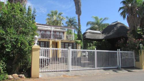 a house with a white fence and palm trees at Victoria Manor in Upington