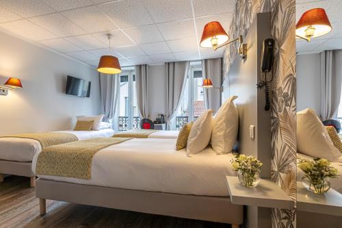 two beds in a hotel room with windows at Splendid Hôtel in Paris