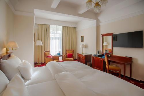 a hotel room with a large white bed and a desk at Ensana Thermia Palace in Piešťany