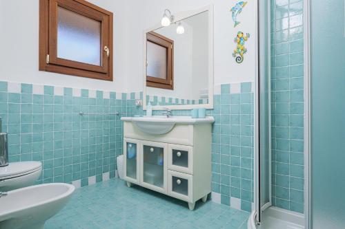 a blue tiled bathroom with a sink and a toilet at Il Balcone su Tavolara in Porto San Paolo