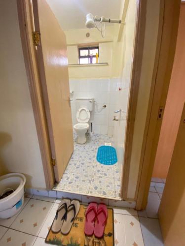 ein Badezimmer mit Toilette und einem Paar Schuhe in der Unterkunft Quiet Comforts in Embu