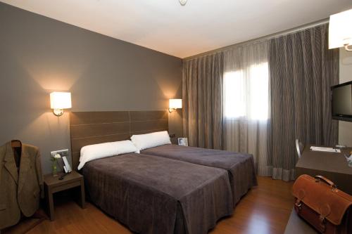 Habitación de hotel con cama y TV en Hotel Cisneros en Alcalá de Henares