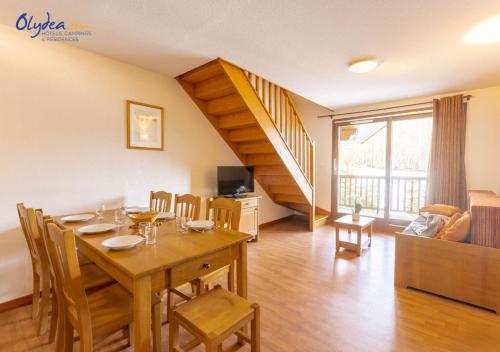 a dining room with a table and chairs and a staircase at Olydea les Bottieres - Saint-Pancrace in Saint-Pancrace