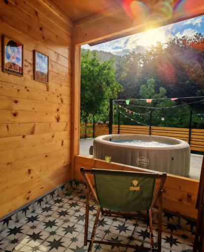 a tub in a room with a window and a chair at Vikendica Jagodica in Ivanjica
