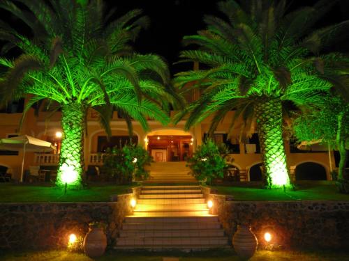 a resort with two palm trees and lights at Fiori Hotel in Gouvia