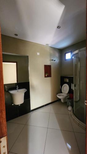 a bathroom with a toilet and a sink at ORO - Boutique Guesthouse in Matola