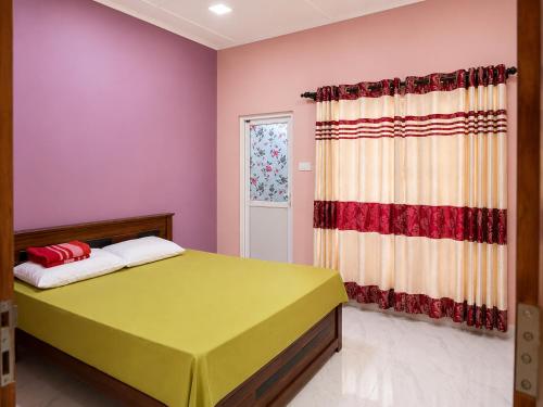 a bedroom with a green bed and pink walls at JB Vin Hotel in Point Pedro