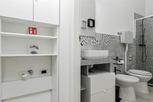 a white bathroom with a toilet and a sink at Appartamenti Corallo e Conchiglia in Olbia