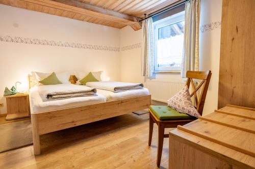 a bedroom with a bed and a chair and a window at Steffi's Landhof in Bad Wörishofen