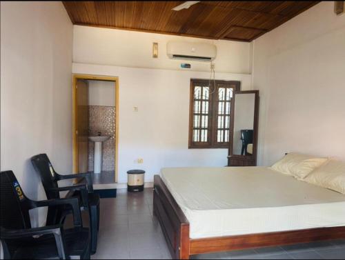 a bedroom with a bed and a desk and chairs at Honey guest Batticaloa in Batticaloa
