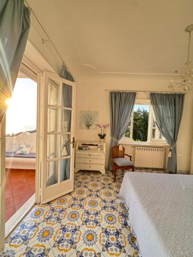a bedroom with a bed and a chair and windows at B&B Villa Cristina in Anacapri