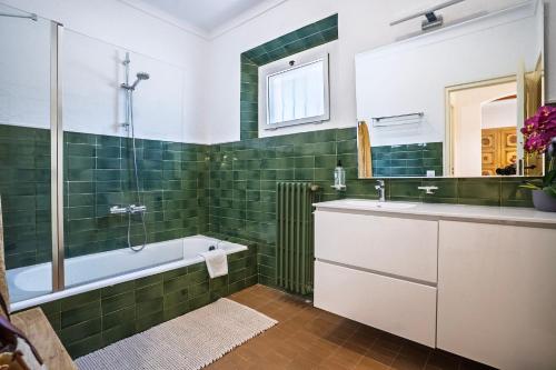 a bathroom with green tiles and a tub and a sink at Torre Sant Genís in Llança